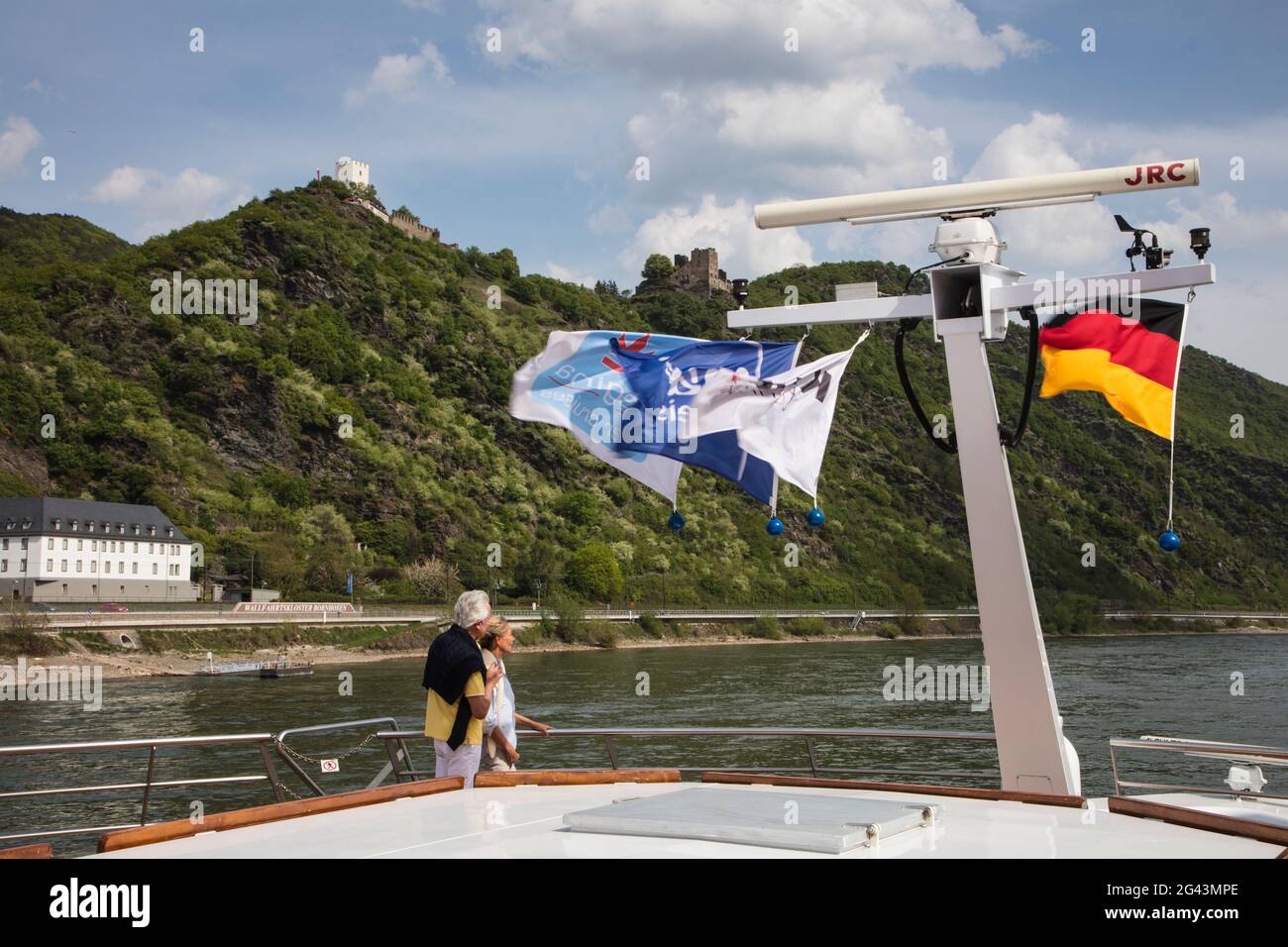 Paar an Deck eines Flusskreuzfahrtschiffes während einer Rheinschifffahrt mit Schloss Sterrenberg und Schloss Liebenstein dahinter, Kamp Bornhofen, Rheinland-P Stockfoto