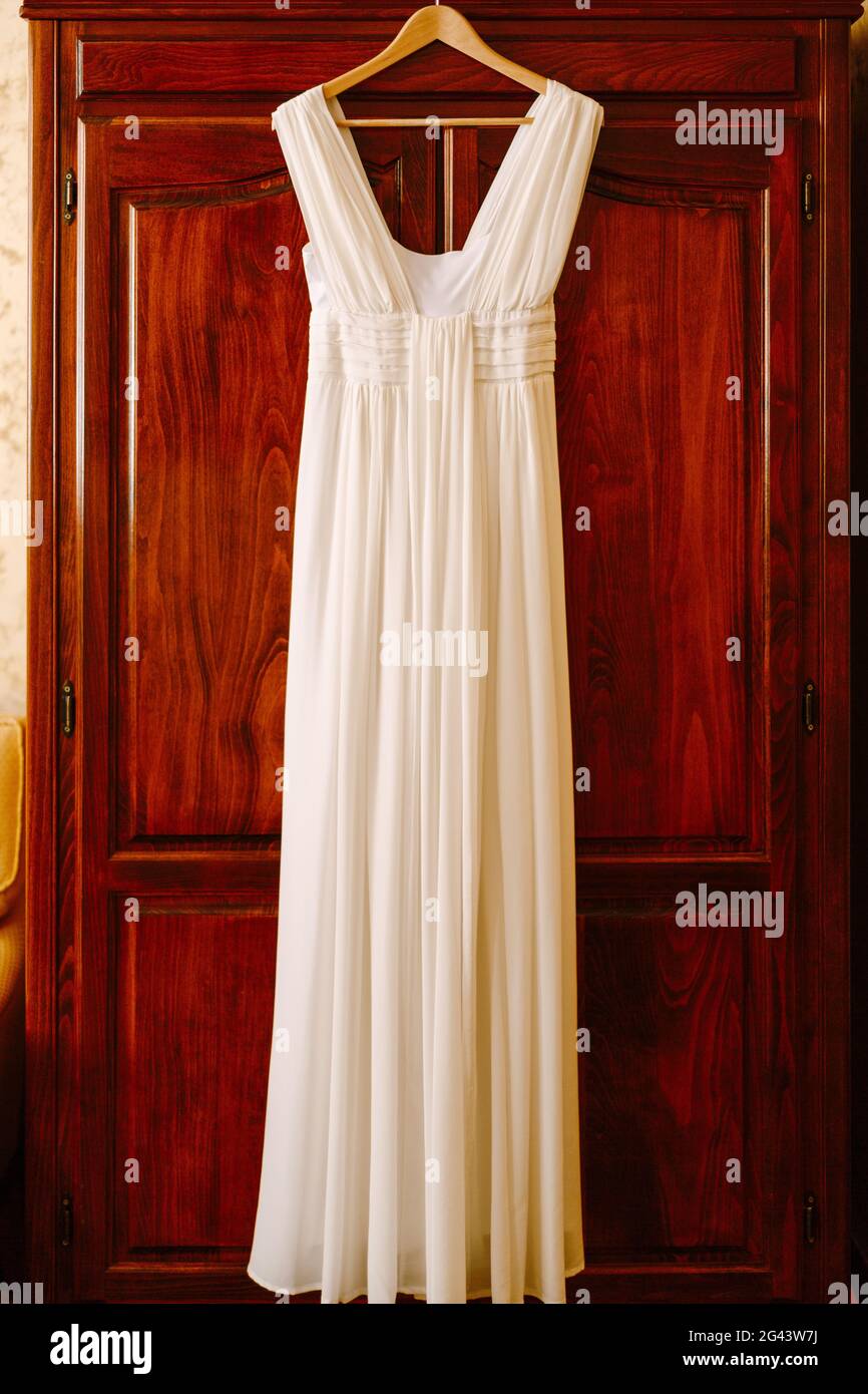 Das Brautkleid im griechischen Stil auf einem Kleiderbügel an einer Holztür. Stockfoto