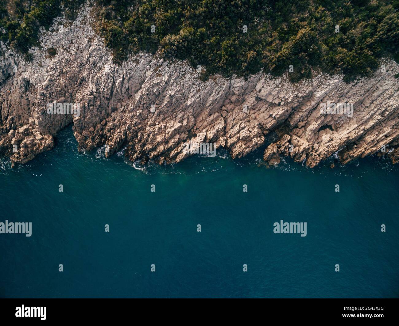 Blick von oben auf die Küste mit Klippen, türkisfarbenem Wasser, Felsen, Schaum, Wellen und Bäumen. Stockfoto