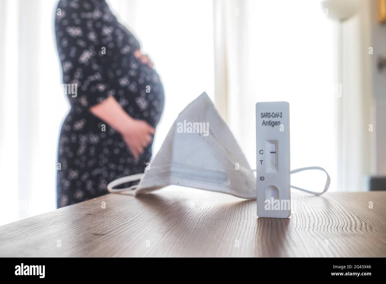 Coronavirus und Covid19 während der Schwangerschaft: Nahaufnahme eines negativen Covid-Antigen-Tests, Schwangere im verschwommenen Hintergrund Stockfoto