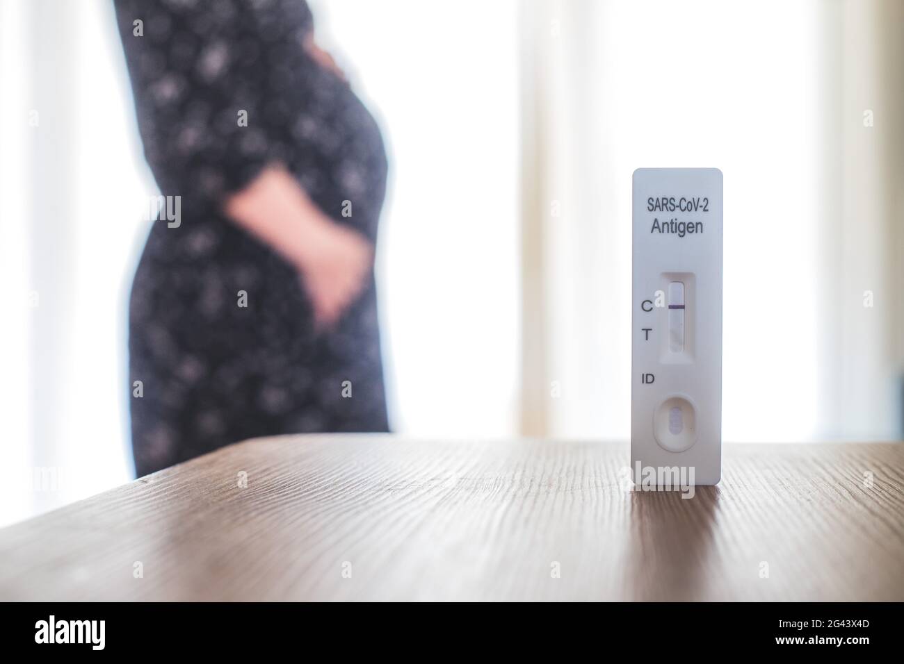 Coronavirus und Covid19 während der Schwangerschaft: Nahaufnahme eines negativen Covid-Antigen-Tests, Schwangere im verschwommenen Hintergrund Stockfoto