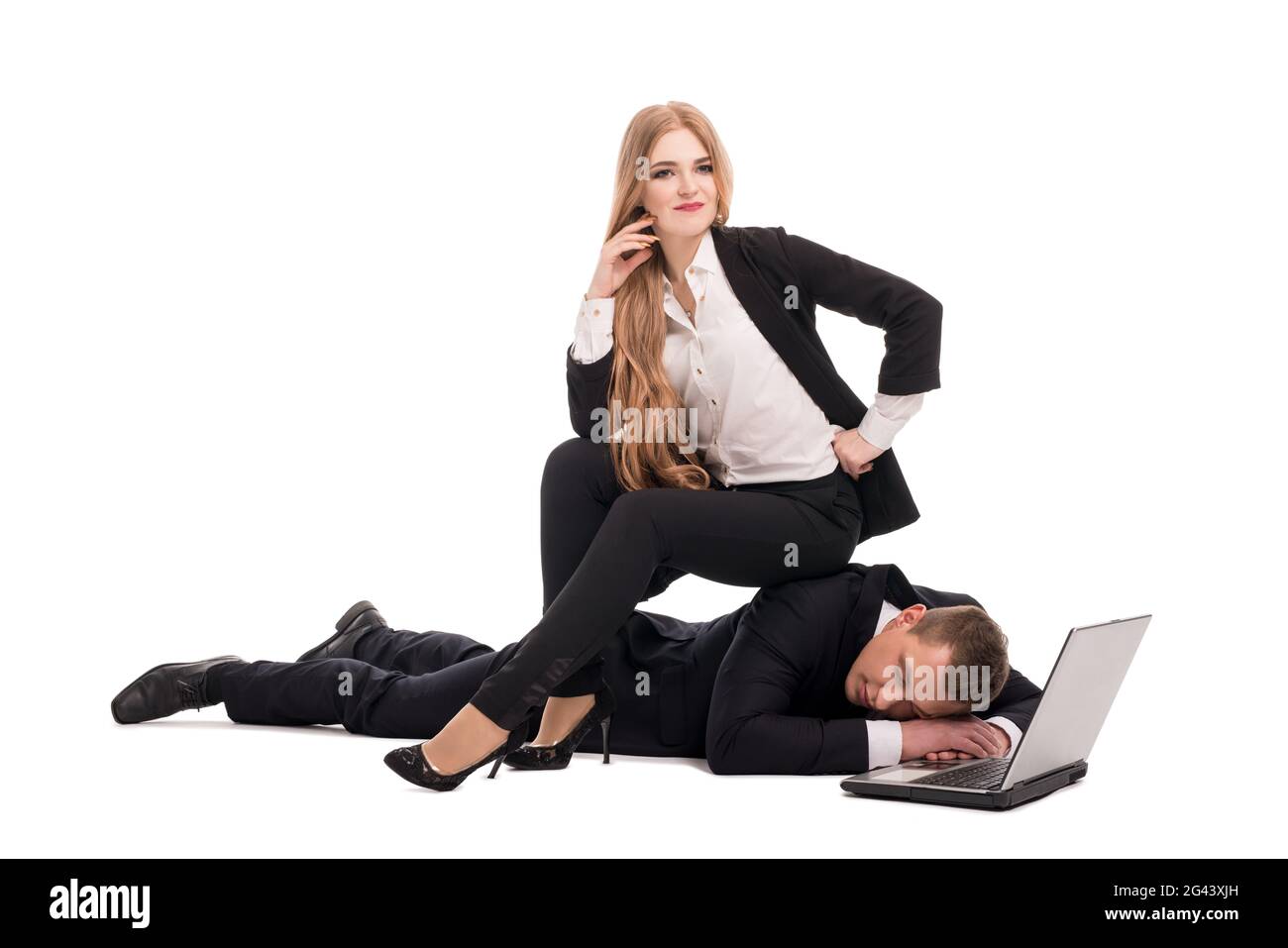 Geschäftsfrau, die auf einem müden Kollegen in der Nähe eines Laptops sitzt Stockfoto