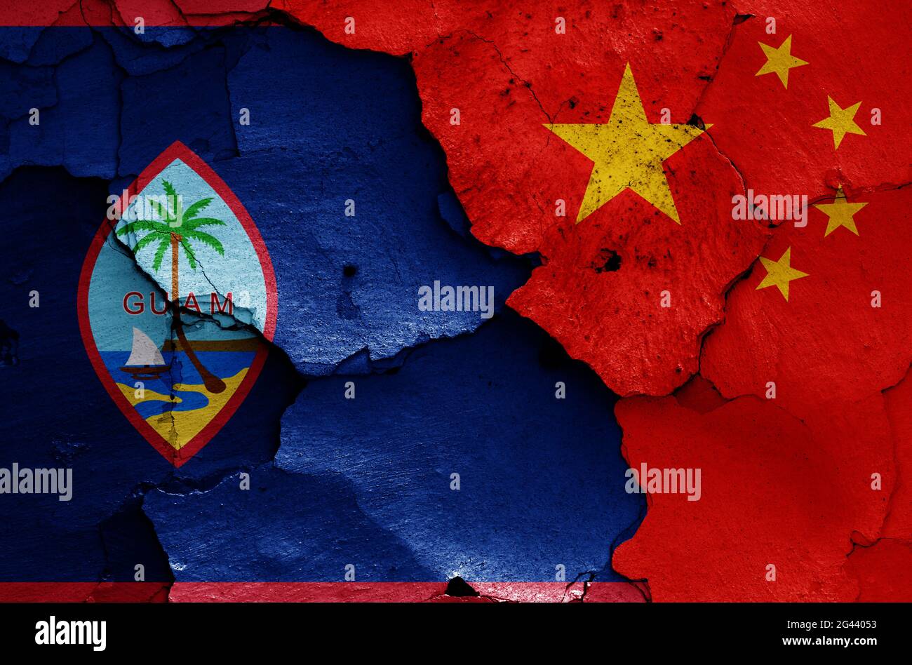Flaggen von Guam und China auf rissige Wand gemalt Stockfoto