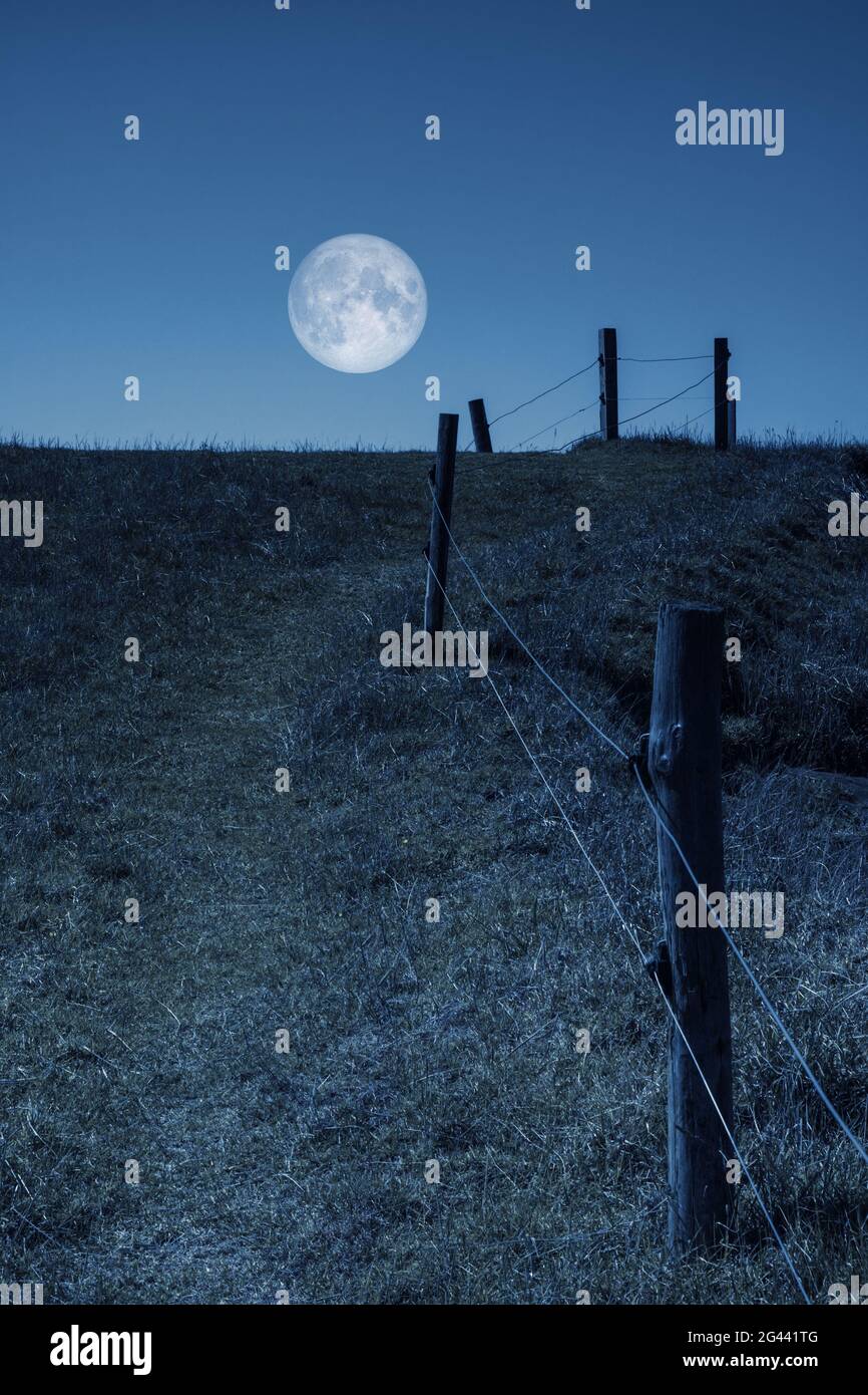 Mond über einem Hügel und einem Zaun Stockfoto