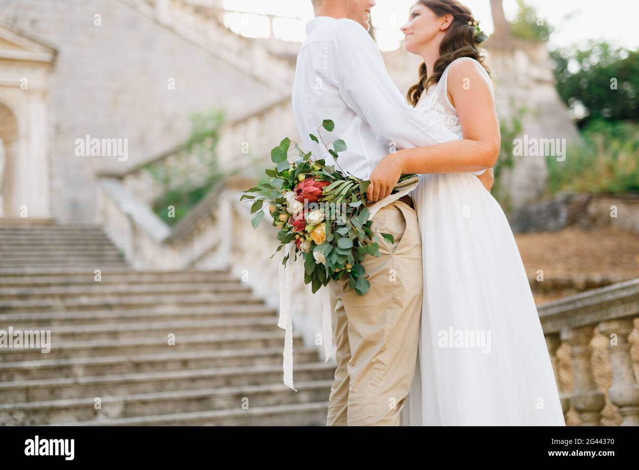 Braut und Bräutigam umarmen auf dem alten Glockenturm in der Nähe der Kirche in Prcanj, Braut hält Hochzeit Strauß in der Hand Stockfoto
