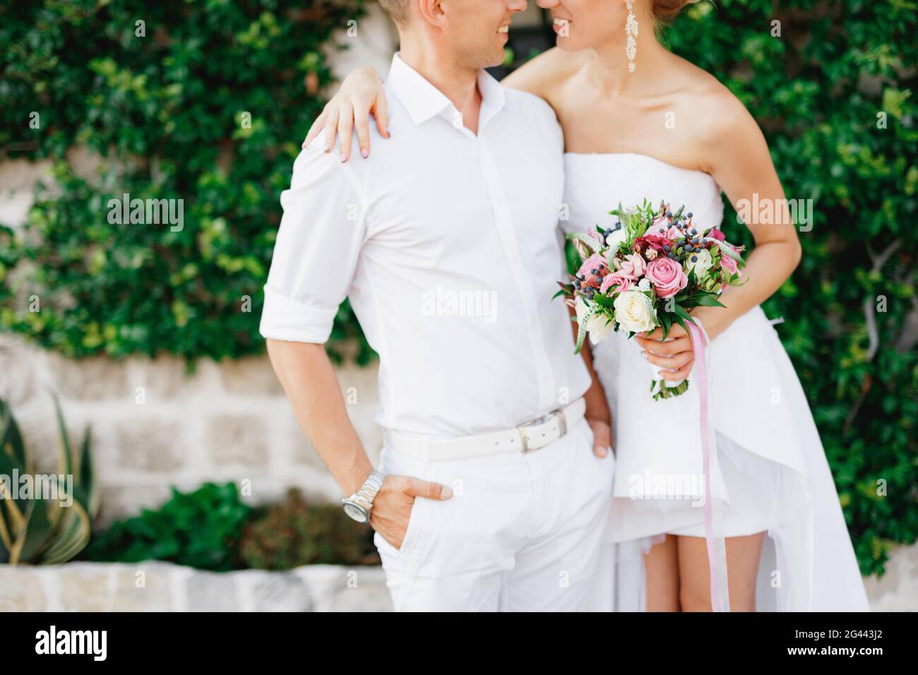 Die Braut und der Bräutigam stehen umarmt in einem schönen efeubedeckten weißen Haus in der Altstadt von Perast, aus nächster Nähe Stockfoto