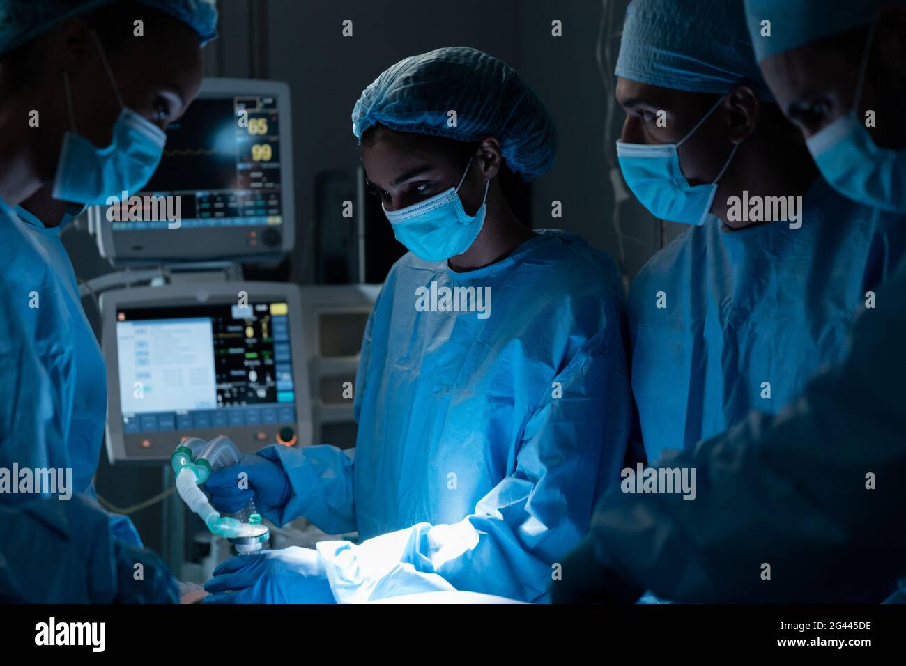 Diverse Chirurgen mit Gesichtsmasken und Schutzkleidung während der Operation Im Krankenhaus Stockfoto