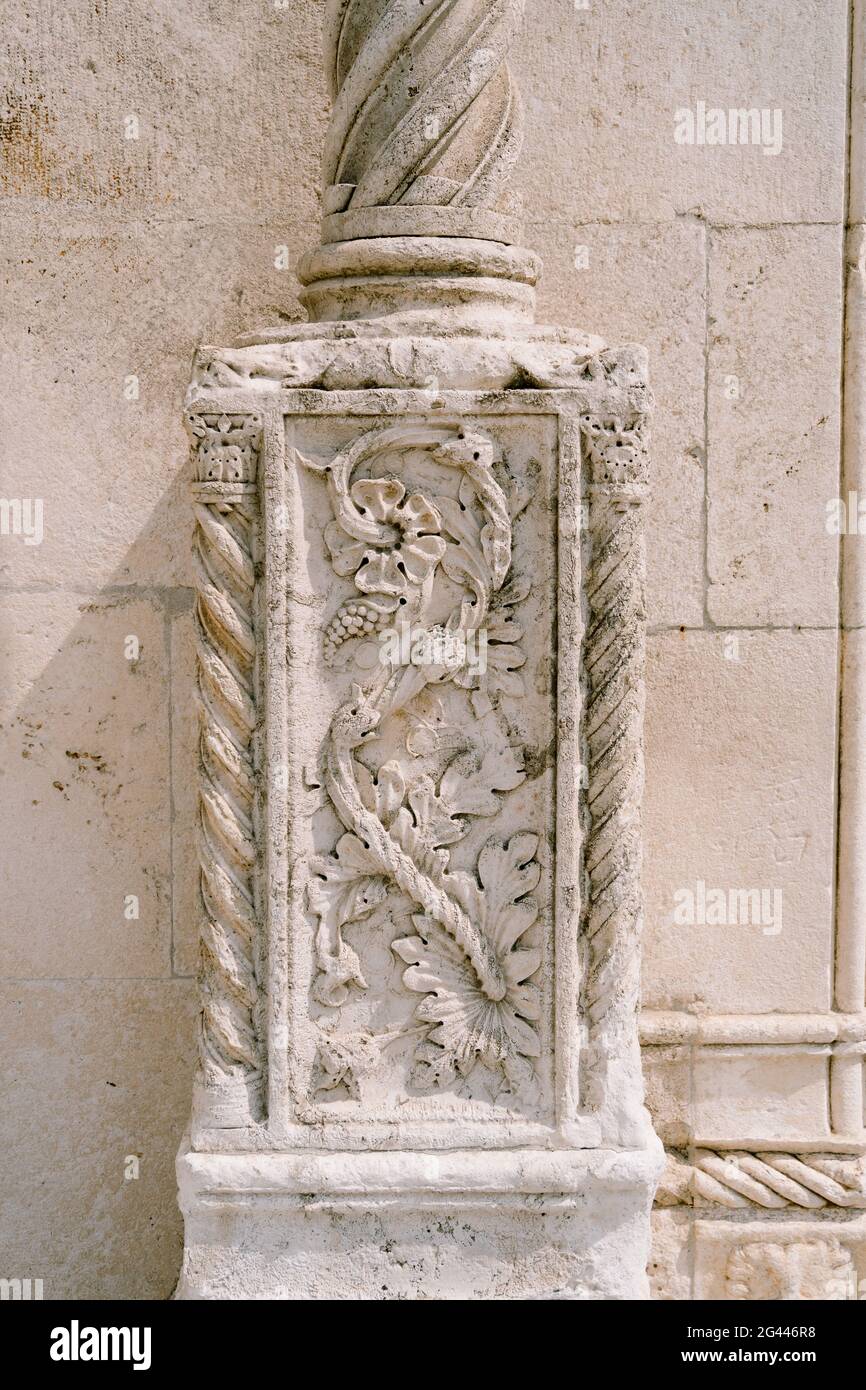 Steinmauer mit einem blumenförmigen Flachrelief an einer Säule. Stockfoto