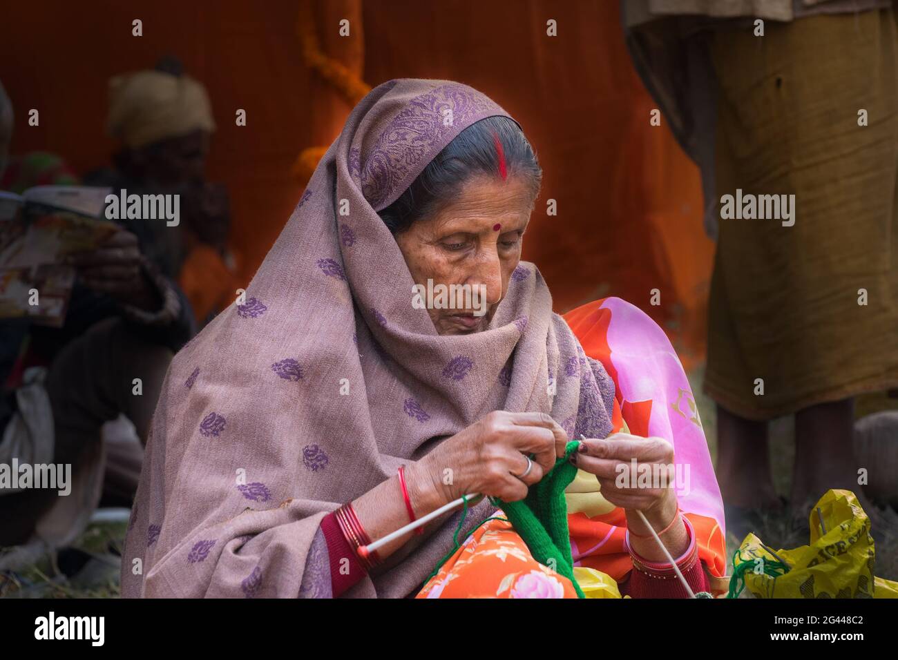 BABUGHAT, KALKUTTA, WESTBENGALEN / INDIEN - 11. JANUAR 2015 : gealterte Inderin, die im Transitlager Gangasagar Wolle strickt. Stockfoto