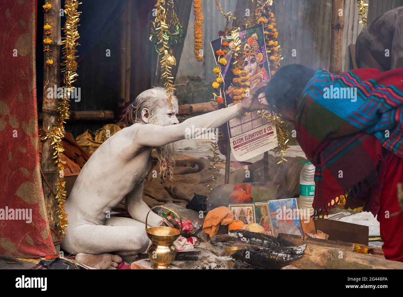 BABUGHAT, KALKUTTA, WESTBENGALEN / INDIEN - 11. JANUAR 2015 : Hindu-Sadhu mit weißer Asche auf Körper und Gesicht, die einen blauen, mit Sari bekleideten indischen Devoten segnet Stockfoto