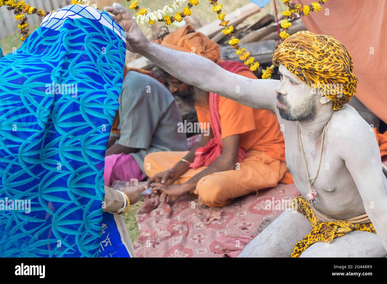 BABUGHAT, KALKUTTA, WESTBENGALEN / INDIEN - 10. JANUAR 2015 : Hindu-Sadhu mit weißer Asche auf Körper und Gesicht, die einen blauen, mit Sari bekleideten indischen Devoten segnet Stockfoto