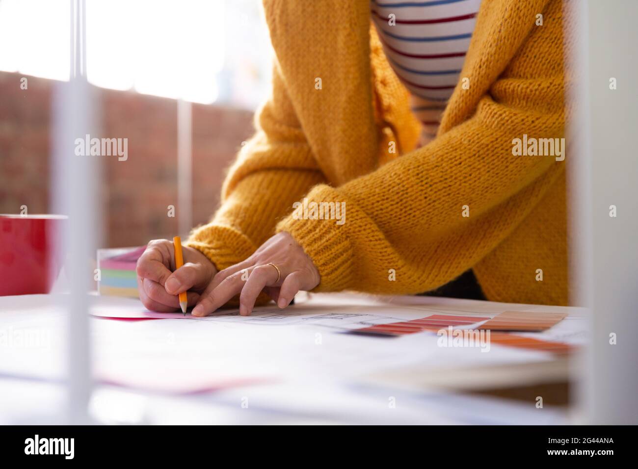 Mittelteil der Geschäftsfrau, die im Büro schreibt und Memonotizen platziert Auf dem Plan Stockfoto