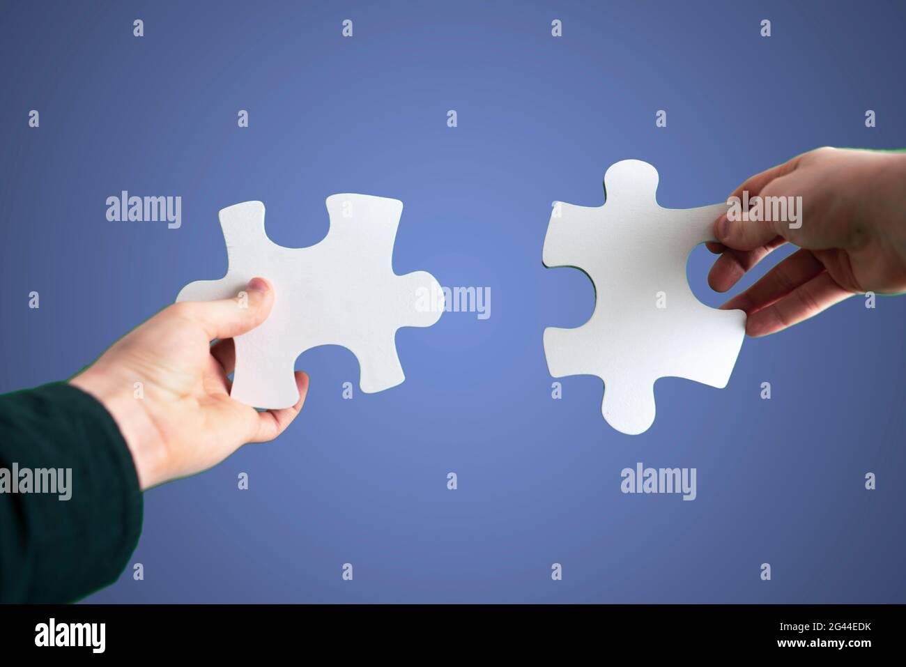 Menschliche Hände verbinden zwei Puzzleteile miteinander, Trockenbau, Himmelshintergrund Stockfoto