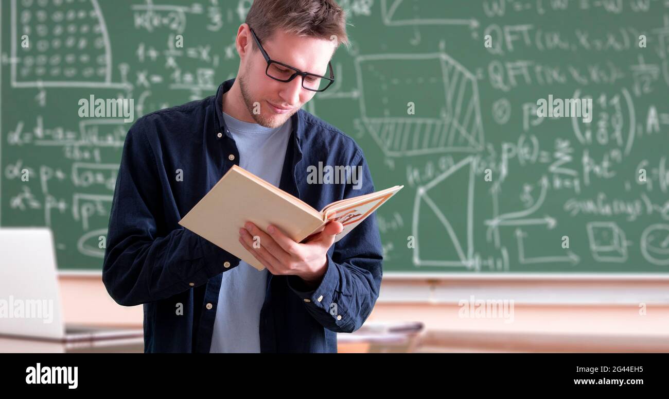 Junger Professor an der Universität mit einem Buch im Klassenzimmer Stockfoto