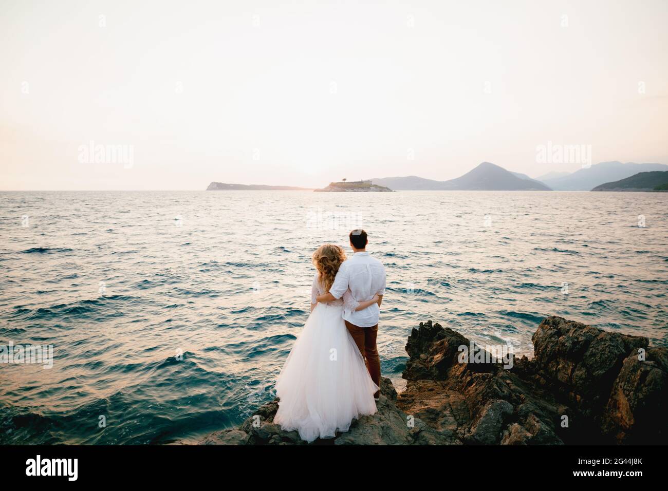 Braut und Bräutigam stehen umarmt auf den Felsen vorbei Das Meer und Blick in die Ferne Stockfoto