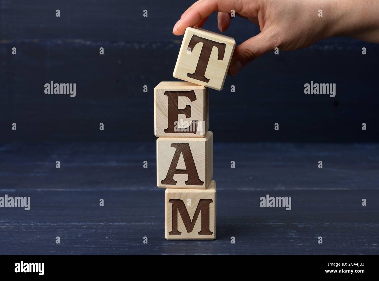 Weibliche Hand hält einen Stab mit dem Inschrift-Team auf blauem Hintergrund. Talentsuchkonzept, Rekrutierung für Unternehmen Stockfoto