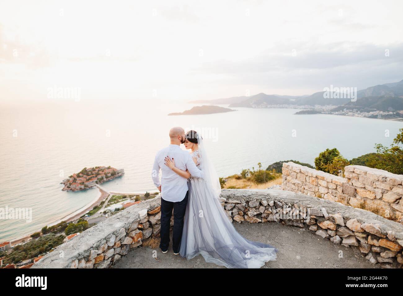 Braut und Bräutigam umarmen sich auf der Aussichtsplattform Mit Blick auf die Insel Sveti Stefan Stockfoto