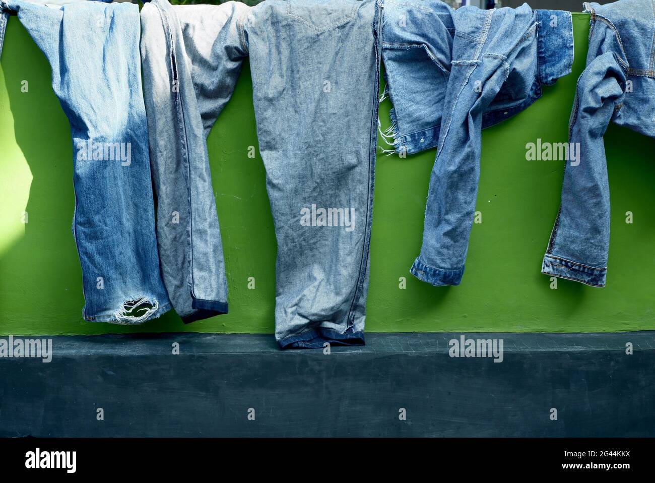 Blaue Jeans-Hosen, die an der Wand getrocknet sind Stockfoto