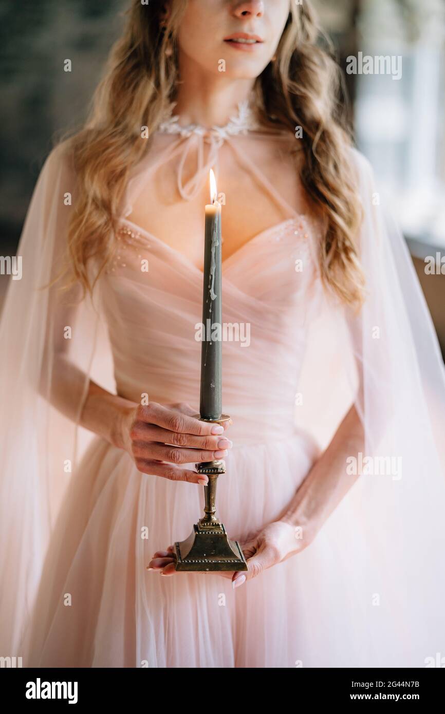 Braut in einem schönen Kleid mit brennender Kerze in Ihre Hände Stockfoto