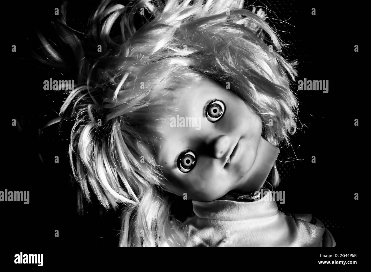 Gruselige Mädchen Puppe Gesicht. Es scheint wie ein Horrorfilm-Charakter zu sein. Wütend Baby Puppe, Angst vor lebenden Geist. Halloween-Konzept. Schwarz Stockfoto