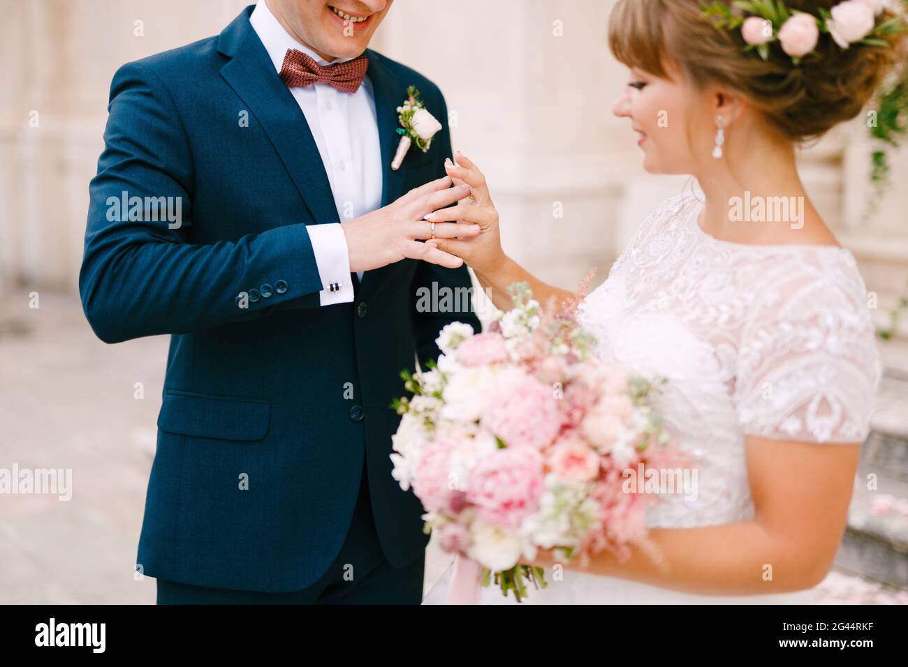 Die Braut legt einen Ring auf den Finger des Bräutigams und Hält während der Hochzeitszeremonie einen Strauß in ihren Händen Stockfoto