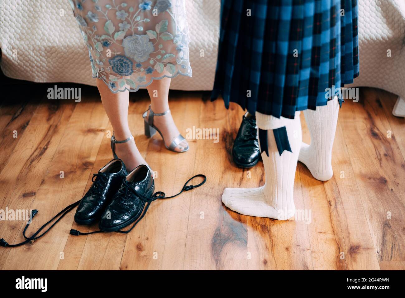 Schottische Hochzeitsvorbereitungen. Der Mann im Kilt steht neben der Frau in einem Rock mit hohen Schuhen. Es gibt Schuhe mit langem l Stockfoto