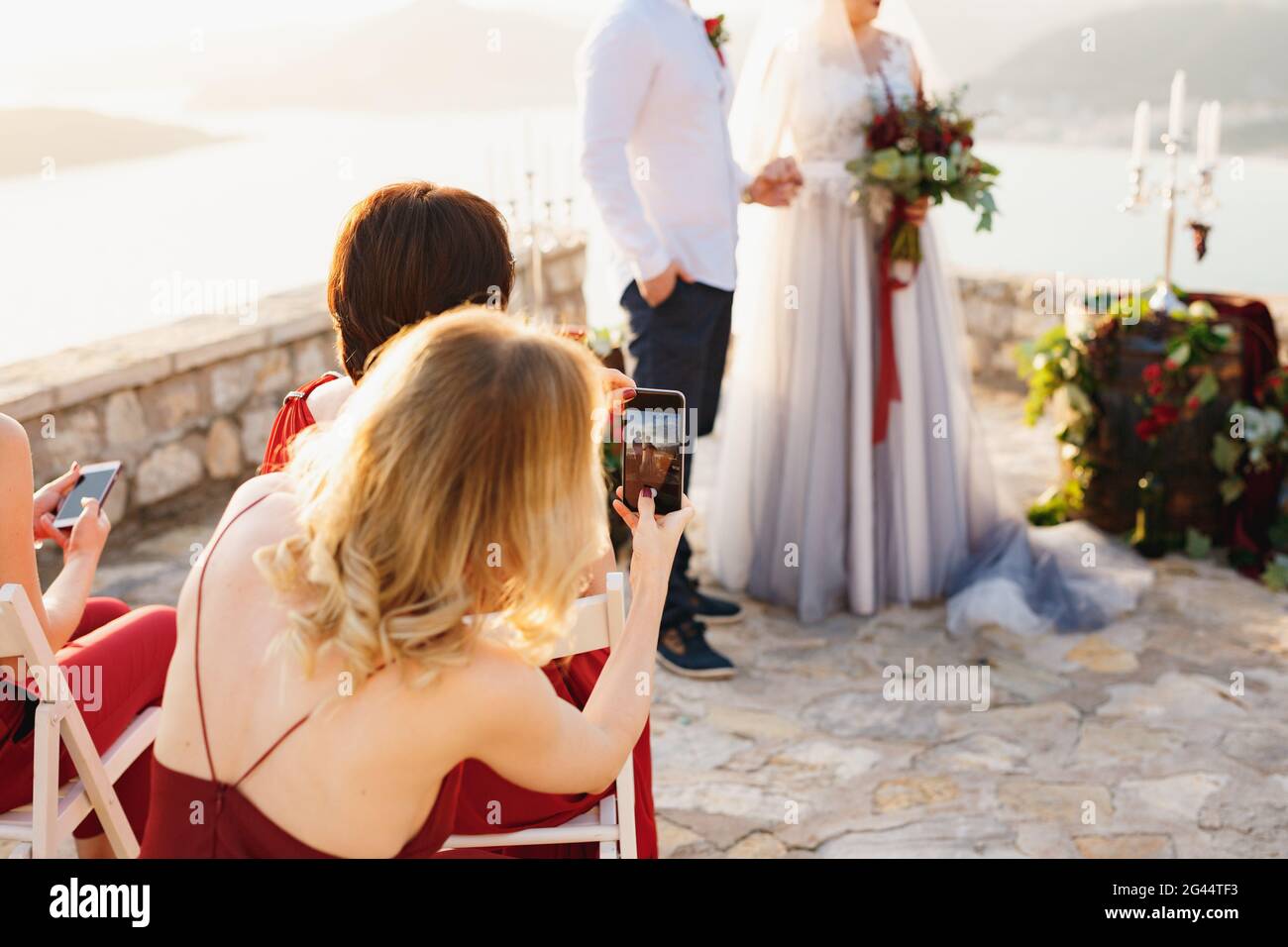 Gäste bei der Hochzeitszeremonie, die Braut und Bräutigam filmten Auf den Telefonen Stockfoto