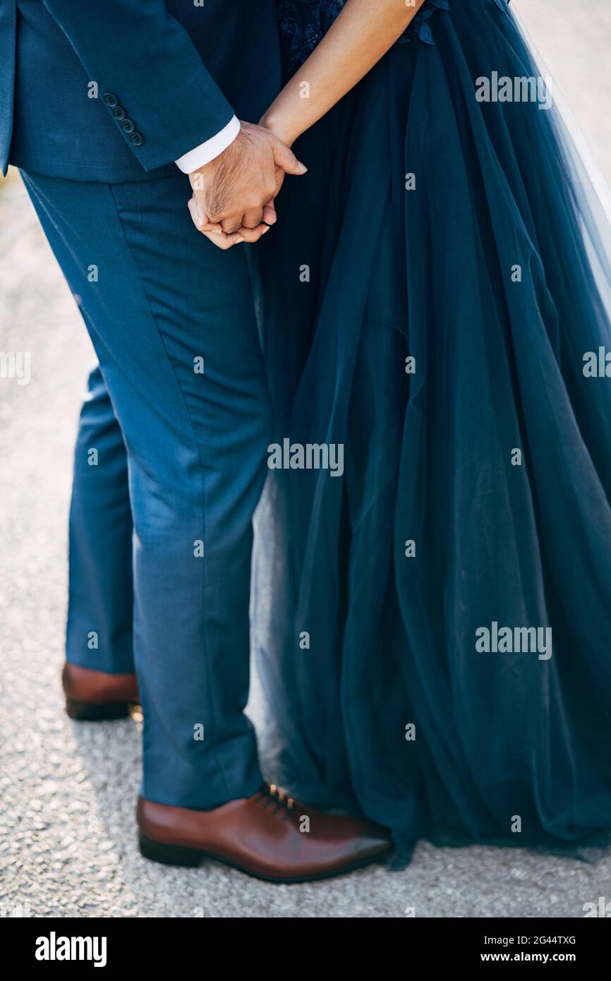 Bräutigam in einem blauen Anzug hält die Hand der Braut in einem blauen Kleid. Nahaufnahme. Ansicht von unten Stockfoto