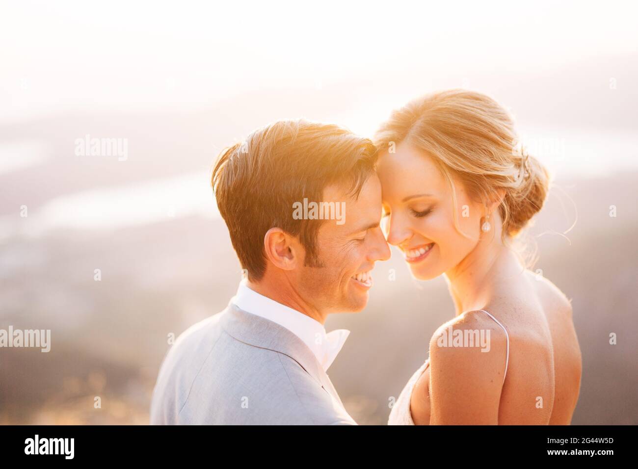 Die Braut und der Bräutigam sitzen auf dem Gipfel des Mount Lovcen mit Blick auf die Bucht von Kotor, lächeln und umarmen sich zärtlich, Nahaufnahme Stockfoto