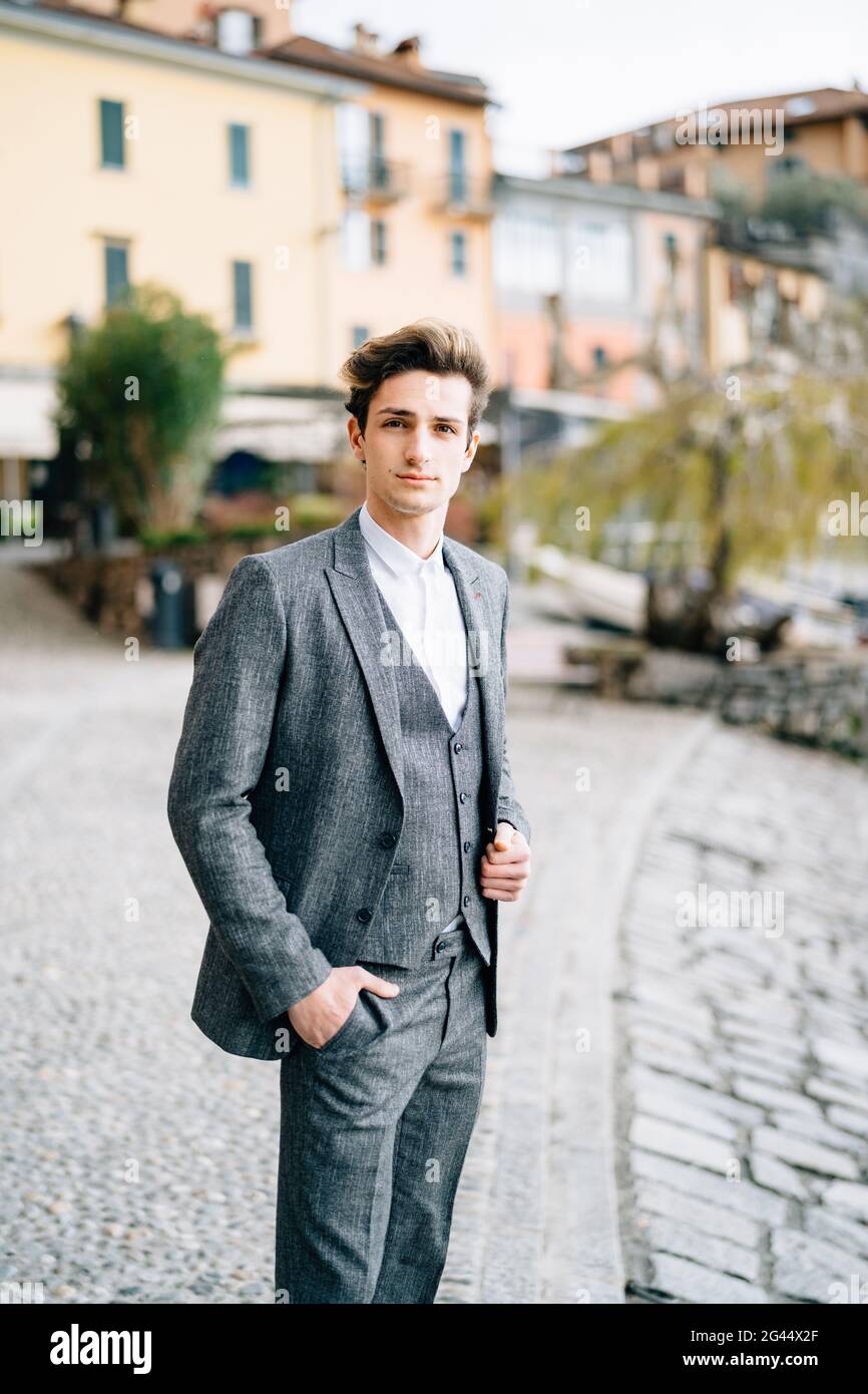 Groom steht auf dem Kopfsteinpflaster der Straße in Varenna vor dem Hintergrund alter Villen. Comer See Stockfoto