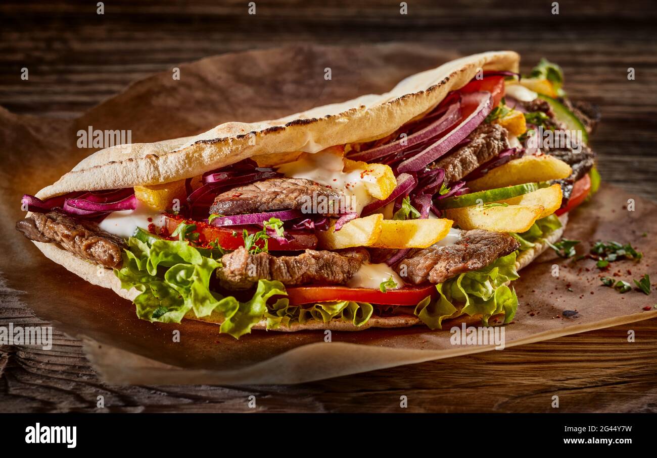 Appetitlich Döner Kebab mit Fleisch und Gemüse auf dem Teller auf Holztisch abgetrennt Stockfoto
