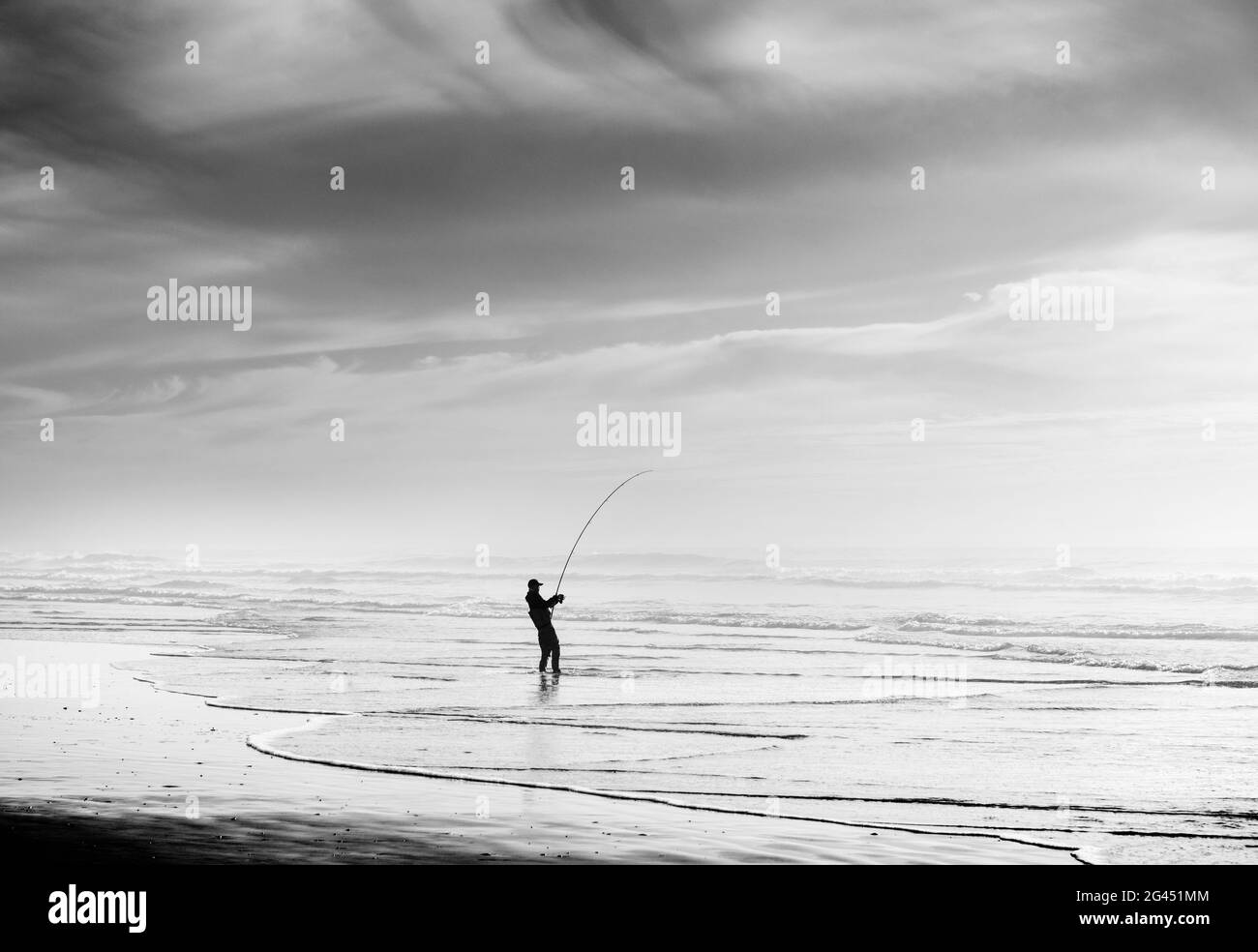 Silhouette des Fischers Angeln am Strand in schwarz und weiß Stockfoto