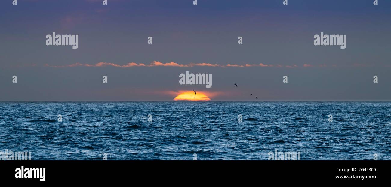 Blauer Pazifischer Ozean unter launischem Himmel bei Sonnenuntergang Stockfoto