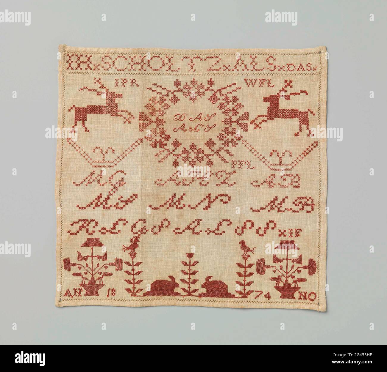 Merklap aus Baumwolle, auf der mit roter Seide IH.scholtz.als.das, verschiedene andere Initialen, springende Hirsche, Blumentöpfe und Kaninchen, anno 1874. Symmetrisch, aber Initialen spiegeln sich nicht. IH.scholtz, die Handwerker; und DLS (in einem Kranz), die Eltern; MG, MS, MN, MB, die Regionen („Männer“). Die Bedeutung der anderen Initialen ist unbekannt. Kaninchen, ob in einem geschlossenen Garten oder nicht, bildeten ein liebes Muster auf den Markensteaks der Kunsthandwerksschulen in Amsterdam. Diese in einer Farbe gestickten Wischtücher unterscheiden sich durch die sorgfältige Arbeitsweise von anderen: Vorder- und Rückseite sind identisch, aber Stockfoto