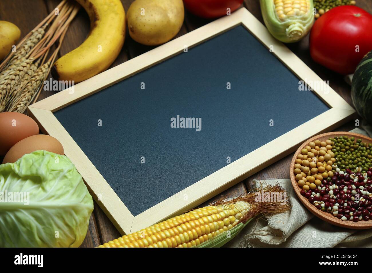 Frisches Bio-Gemüse, Obst, Eier, Bohnen und Hühneraugen mit Tafel auf einem Holztisch Stockfoto