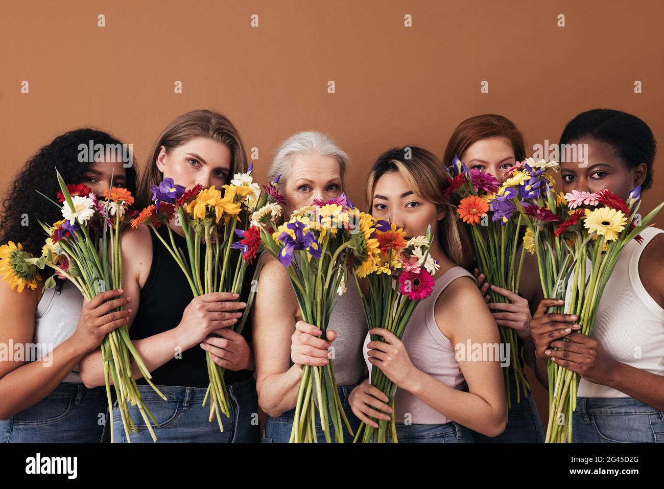 Eine Gruppe verschiedener Frauen versteckt ihre Gesichter durch Blumensträuße. Porträt von sechs Weibchen einer anderen Rasse, eines anderen Alters und eines anderen Figurentyps. Stockfoto