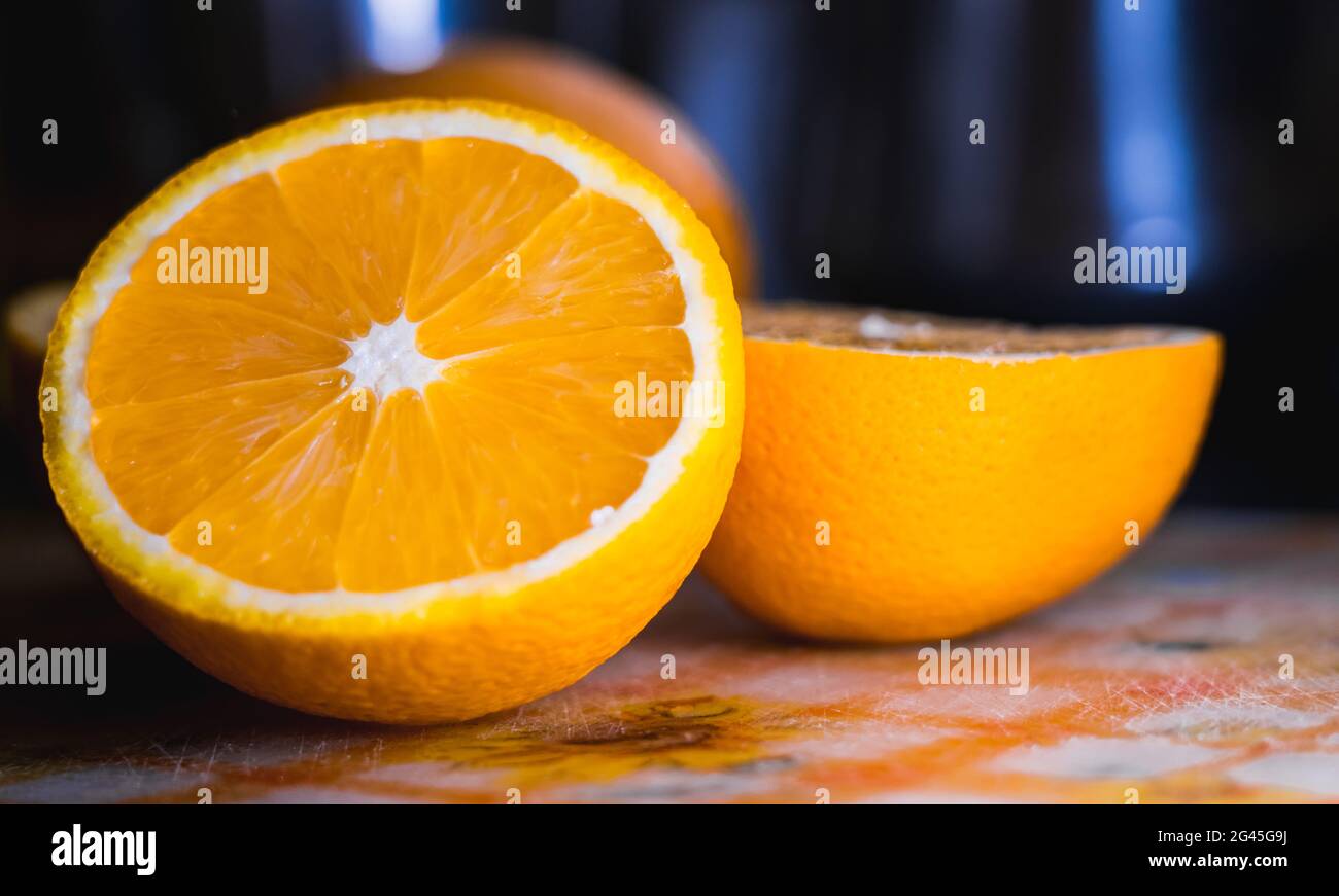 Nahaufnahme einer Orange, die in zwei Hälften geschnitten und auf einem Schneidebrett aus Kunststoff mit verschwommenem Hintergrund platziert wurde. Stockfoto