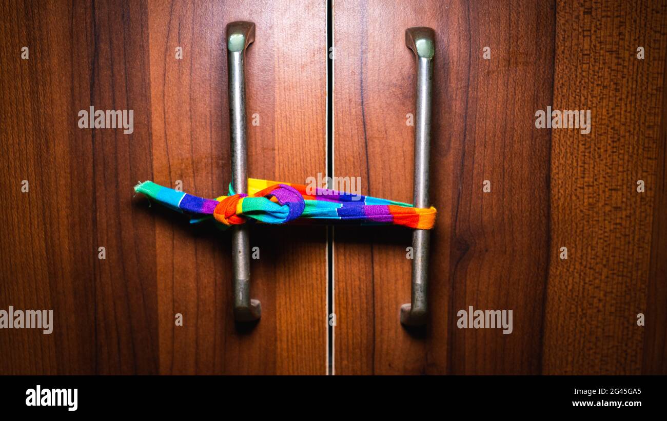 Ein Regenbogentuch, das an einen Türgriff gebunden ist, um den Pride Month zu repräsentieren. Stockfoto