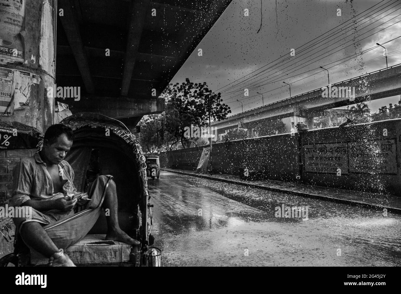 Ein Rikscha-Abzieher zählt neben der Straße verdienen an einem regnerischen Tag Ich habe dieses Bild am 21. Oktober 2020 aus Khilgaon, Dhaka, Bangladesch, South A Stockfoto