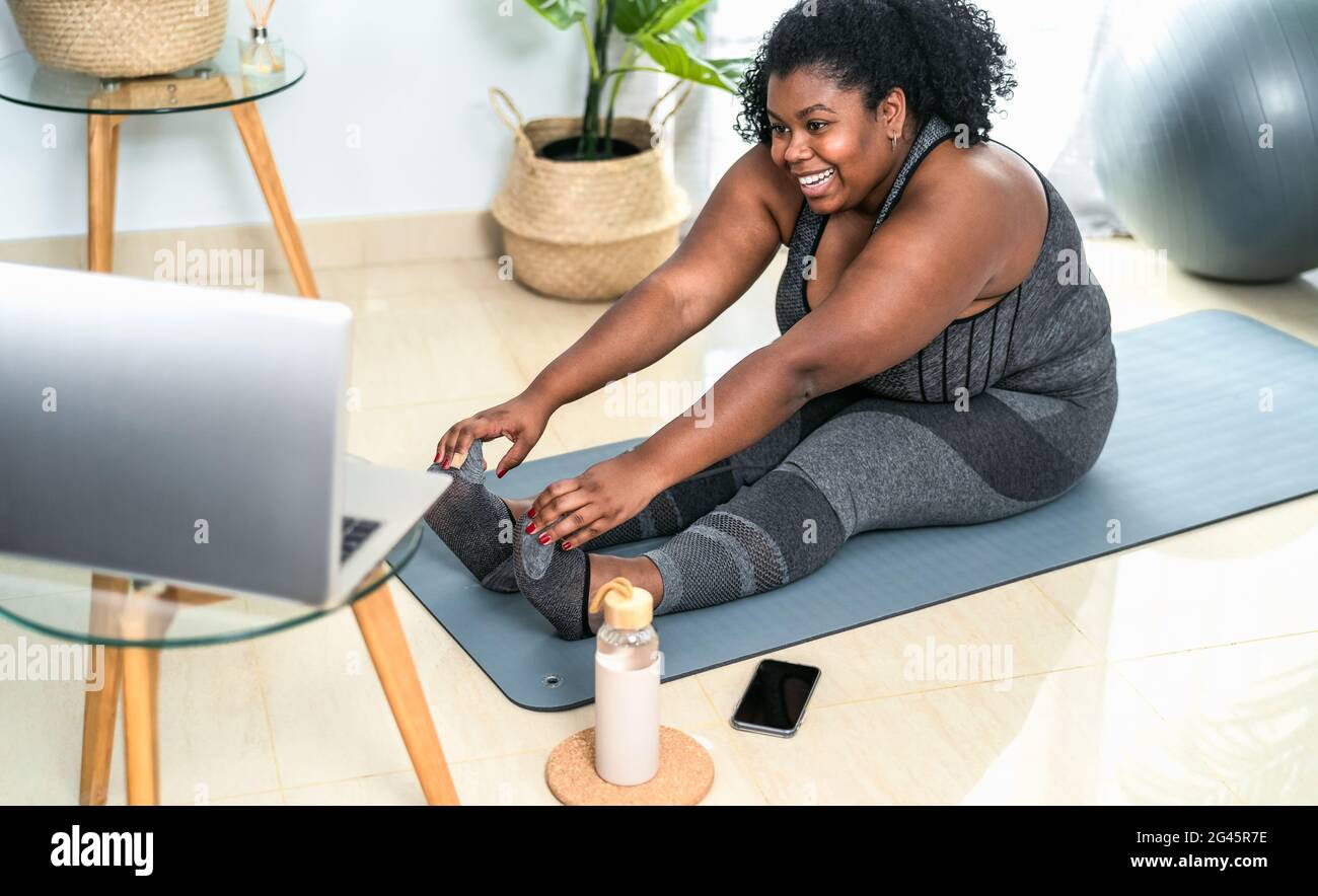 Junge afrikanische kurvige Frau tun Pilates online Fitness-Klasse mit Laptop zu Hause - Sport Wellness People Lifestyle Konzept Stockfoto
