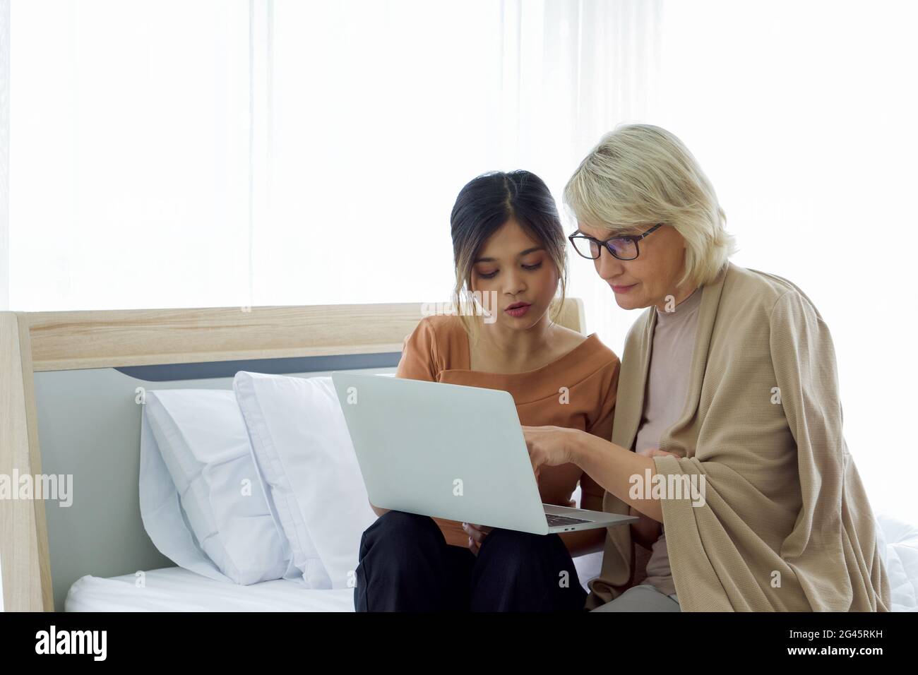 Asiatische Tochter lehren sie angenommen kaukasischen Mutter, wie man im Internet von einem Laptop-Computer zu surfen. Happy Mix Haut Familie zusammen leben. Stockfoto