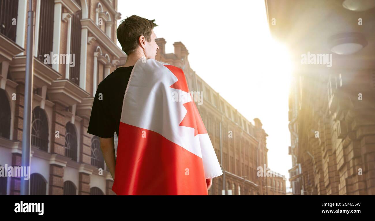 Junger Mann mit einer kanadischen Nationalflagge auf den Seelenhulden, Patriotismus und stolzen Gefühlen Stockfoto