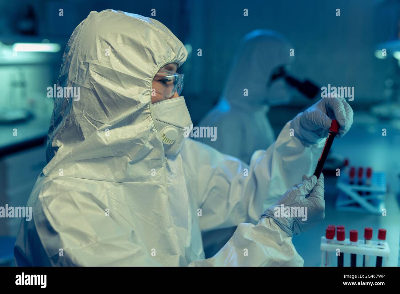 Wissenschaftler oder Chemiker in Overalls, die Staubsauger mit Biomaterial halten Stockfoto