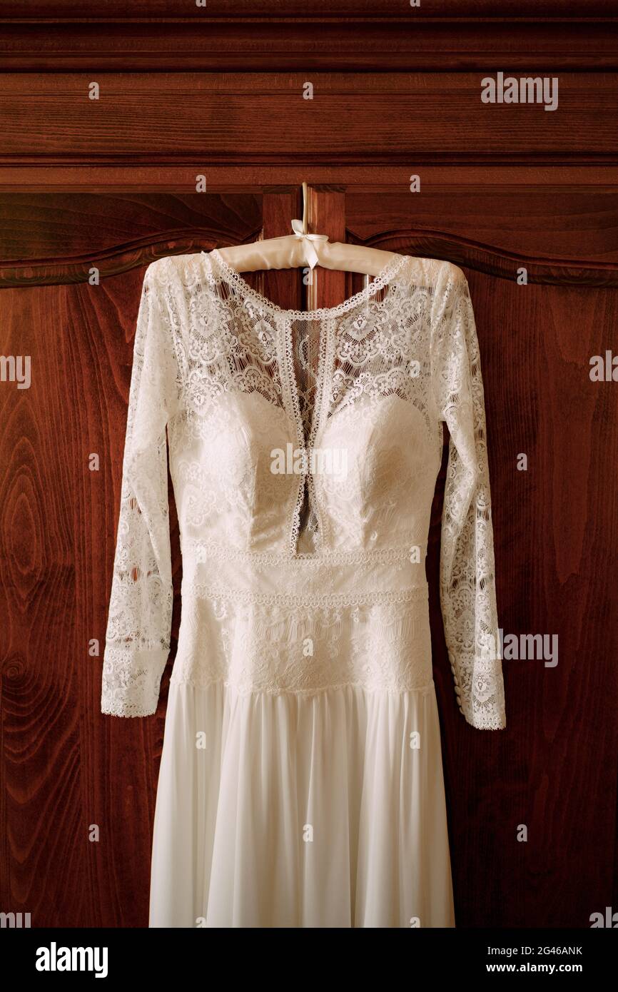 Hochzeitskleid mit Spitze an einer braunen Holztür. Stockfoto