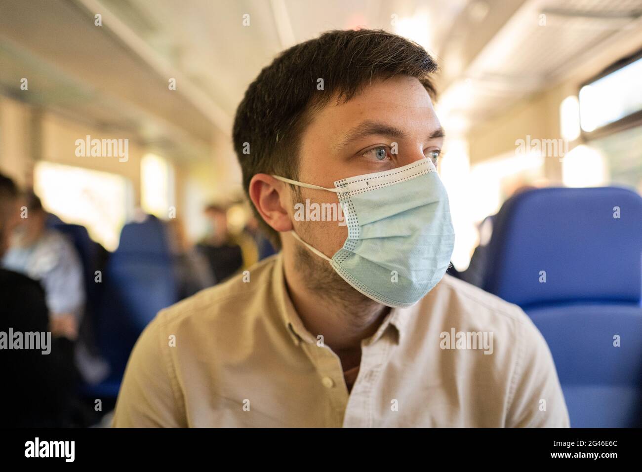 Mann, der mit dem Zug unterwegs ist und eine Gesichtsmask trägt. Soziale Distanzierung bei Bahnreisen während der Covid-19-Pandemie. Männlich pendeln nach Stockfoto