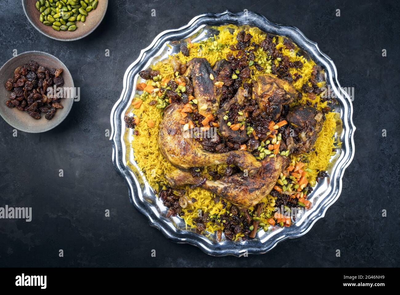Traditionelle gebratene arabische Hähnchen-Majboos mit Hühnerschenkel und Schmuckreis, serviert von oben in einem rustikalen orientalischen Tablett Stockfoto
