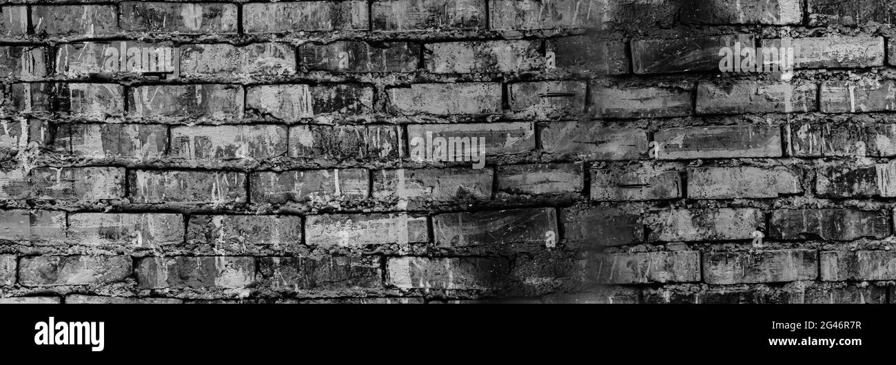 Schwarzer Grunge-Hintergrund. Schwarze alte Backsteinmauer. Dunkelgraue Steinwand. Zusammenbrechendes Mauerwerk. Verwitterte Steinmauer. Stockfoto