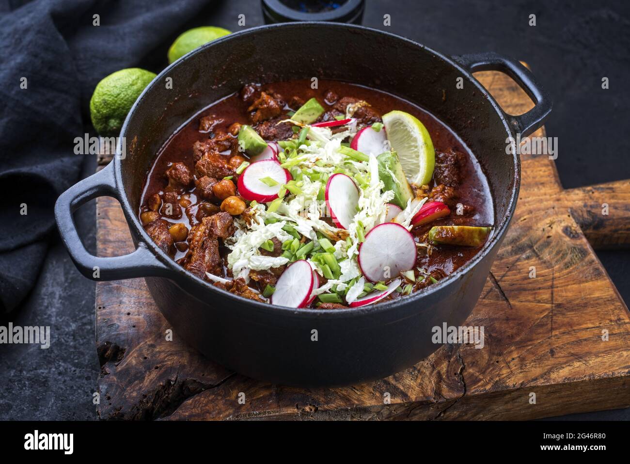 Traditionelle langsam gekochte mexikanische Pozole rojo als Draufsicht in einem modernen Design gusseisernen Bräter auf einem alten rustikalen Holzbrett Stockfoto