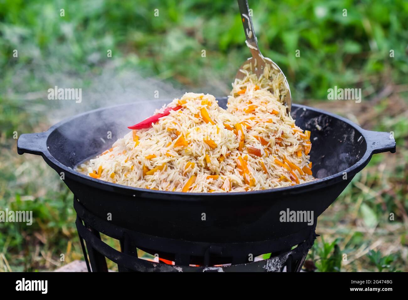 Kochen von Reis Pilaf in einem großen gusseisernen Topf in Brand Stockfoto