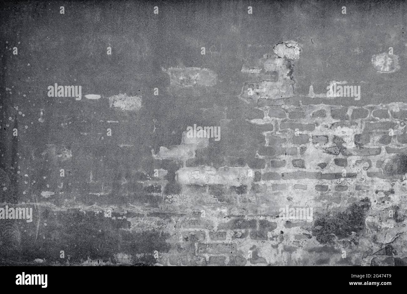 Vorderansicht einer alten, schmutzigen, beschädigten und verputzten Wand. Der Putz ist teilweise abgeschält und zeigt alte Ziegelsteine. Texturierter Hintergrund im Vollformat in Schwarz-Weiß. Stockfoto